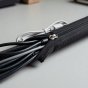 Hands zipping a black cable sleeve closed around power, HDMI and USB cords